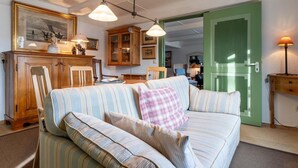 A cozy living room with a striped sofa, wooden cabinet, and a green door. - charmante Ferienwohnung am Hafen (Tönning)