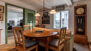 A dining area with a wooden table and chairs, a bench, pendant lights, a clock, and a window with a view. - charmante Ferienwohnung am Hafen (Tönning)
