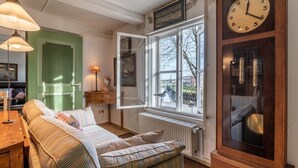 A cozy room with a large bed, a window with a view, a wooden clock, and a green door. - charmante Ferienwohnung am Hafen (Tönning)