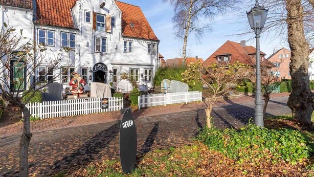 A traditional European building with a red-tiled roof, a white picket fence, and a street lamp. - charmante Ferienwohnung am Hafen (Tönning)