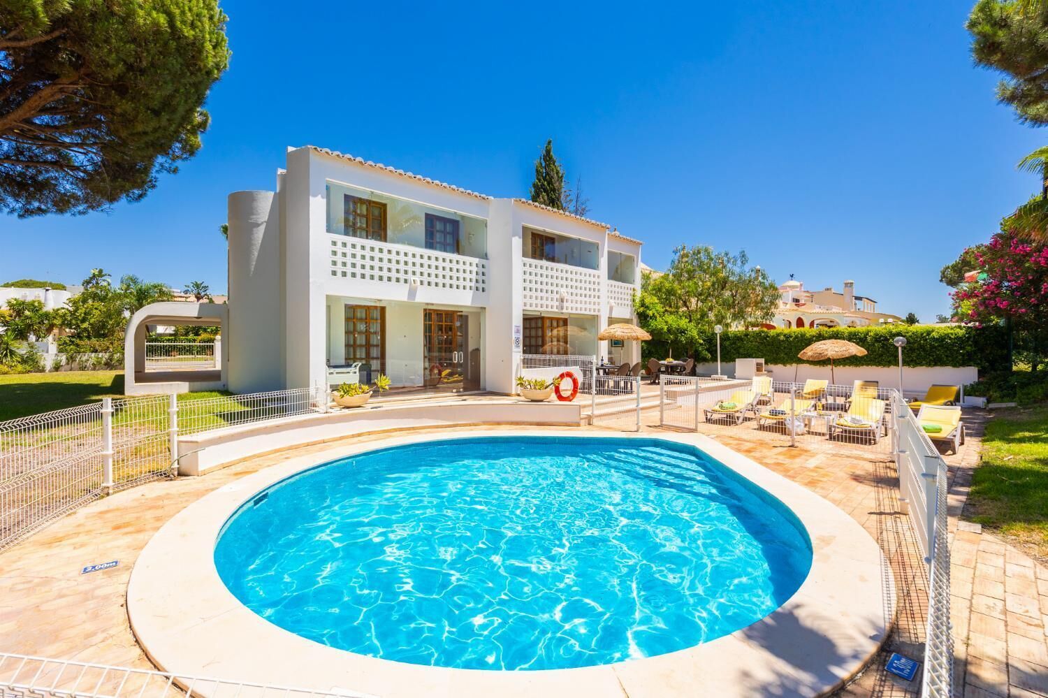 A modern hotel with a swimming pool, outdoor seating, and a well-maintained garden.