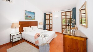 A hotel room with a bed, bedside tables, a desk, a chair, a window with curtains, and a painting on the wall. - Villa Mexico - Four Bedroom Villa, Sleeps 8 (Quarteira)