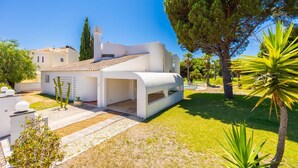 A modern white house with a covered patio, surrounded by a well-maintained lawn and trees. - Villa Mexico - Four Bedroom Villa, Sleeps 8 (Quarteira)