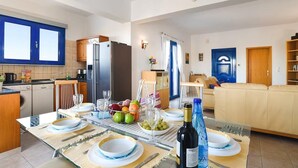 A modern kitchen with a dining area set for a meal, featuring a table with plates, cutlery, and a bottle of wine.