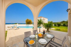 Une table dressée pour deux personnes, avec vue sur une piscine et un bâtiment en arrière-plan.