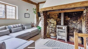 A cozy living room with a modern sofa, a fireplace, and a wood-burning stove. - Beautiful Haven Retreat in Sandwich (Sandwich)
