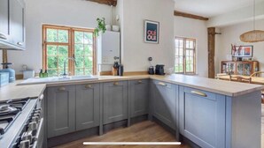 A kitchen with grey cabinets, a wooden floor, and a window with a view of greenery. - Beautiful Haven Retreat in Sandwich (Sandwich)