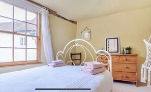 A bedroom with a bed, a wooden dresser, a framed picture, and a window with curtains. - Beautiful Haven Retreat in Sandwich (Sandwich)
