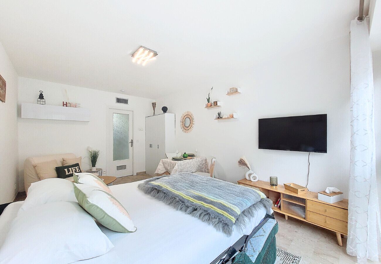 Une chambre moderne comprenant un lit, une table de chevet, une télévision et un petit espace bureau.