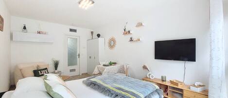 Une chambre moderne comprenant un lit, une table de chevet, une télévision et un petit espace bureau.