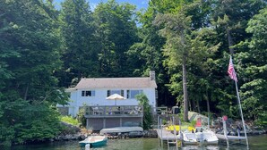 A house with a dock and boats, surrounded by dense trees. - Winnipesaukee Heirloom Cottage (Meredith)