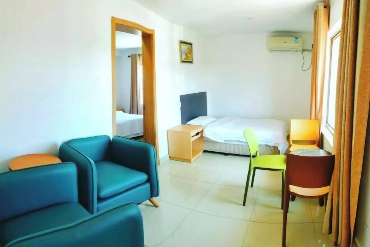 A hotel room with a bed, a desk, a chair, and a sofa.