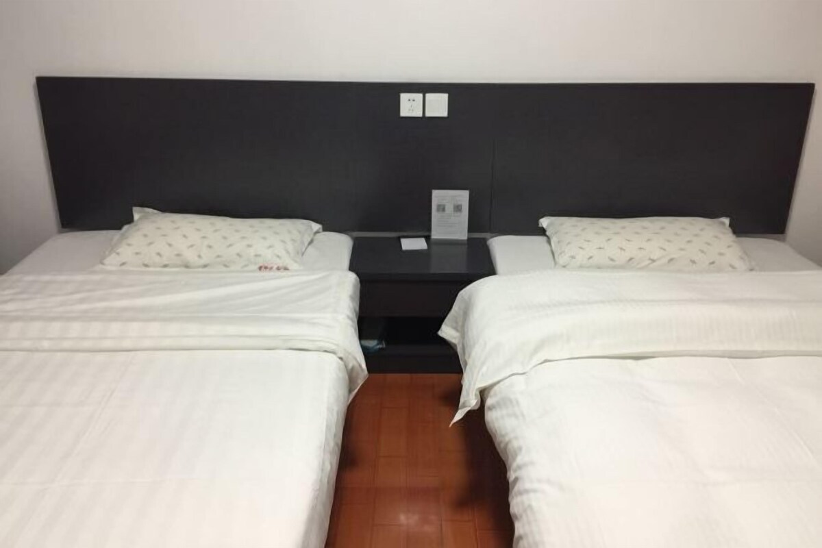 Une chambre double avec deux lits, une petite table et une tête de lit dotée d’un panneau de commande.