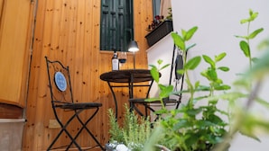 Une porte en bois, une table avec des chaises, une lampe et des plantes en pot.