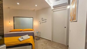 Une chambre d’hôtel comprenant un lit, une petite table, un élément de décoration murale et un appareil de climatisation.
