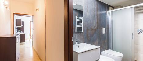 A modern bathroom with a sink, two toilets, and a shower area.