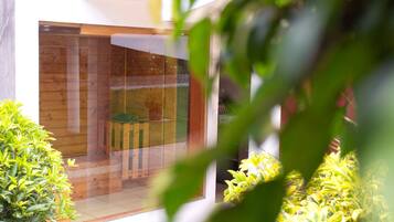A modern interior with a wooden floor, a glass door, and a small seating area.