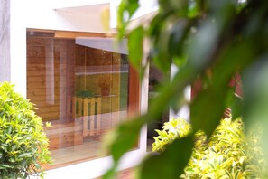 A modern interior with a wooden floor, a glass door, and a small seating area. - HOTEL QUINTA KRYSTAL BOUTIQUE (Sangolqui)