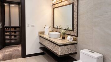 Une salle de bain moderne avec un lavabo sur pied, un grand miroir et des toilettes.