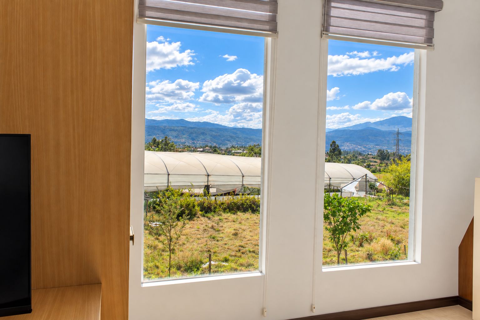 Una habitación con un ventanal grande que da a un invernadero y un paisaje montañoso.