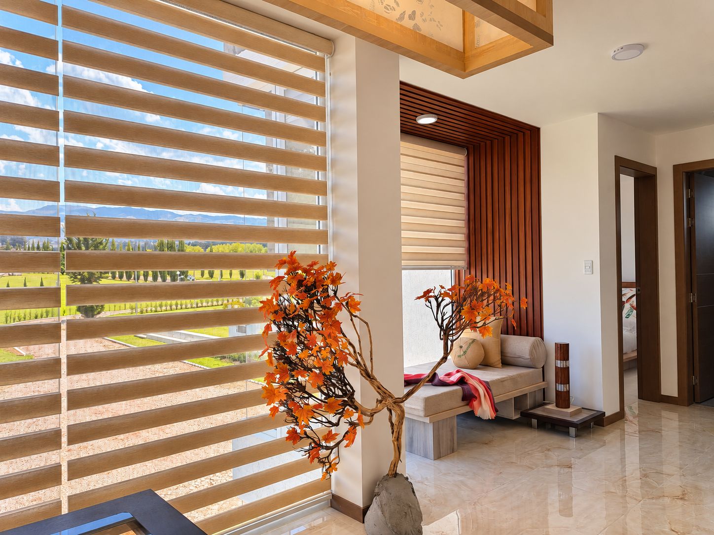 A modern interior with a large window, a seating area with a bench, and a decorative plant.