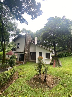 Stunning two-story building with a serene natural setting, featuring a well-maintained lawn and lush greenery.