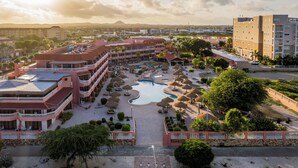 A hotel with multiple balconies, a swimming pool, and a landscaped garden area. - Paradise Beach Villas (Oranjestad)