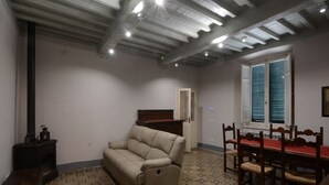 A room with a sofa, dining table, and chairs, wooden floor with patterned tiles, and a ceiling with exposed beams and recessed lighting. - GREAT APARTMENT IN THE HISTORIC CENTER OF CAMAIORE (Camaiore)