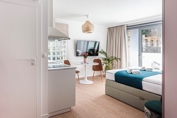 A modern hotel room with a bed, a dining table, and a TV.