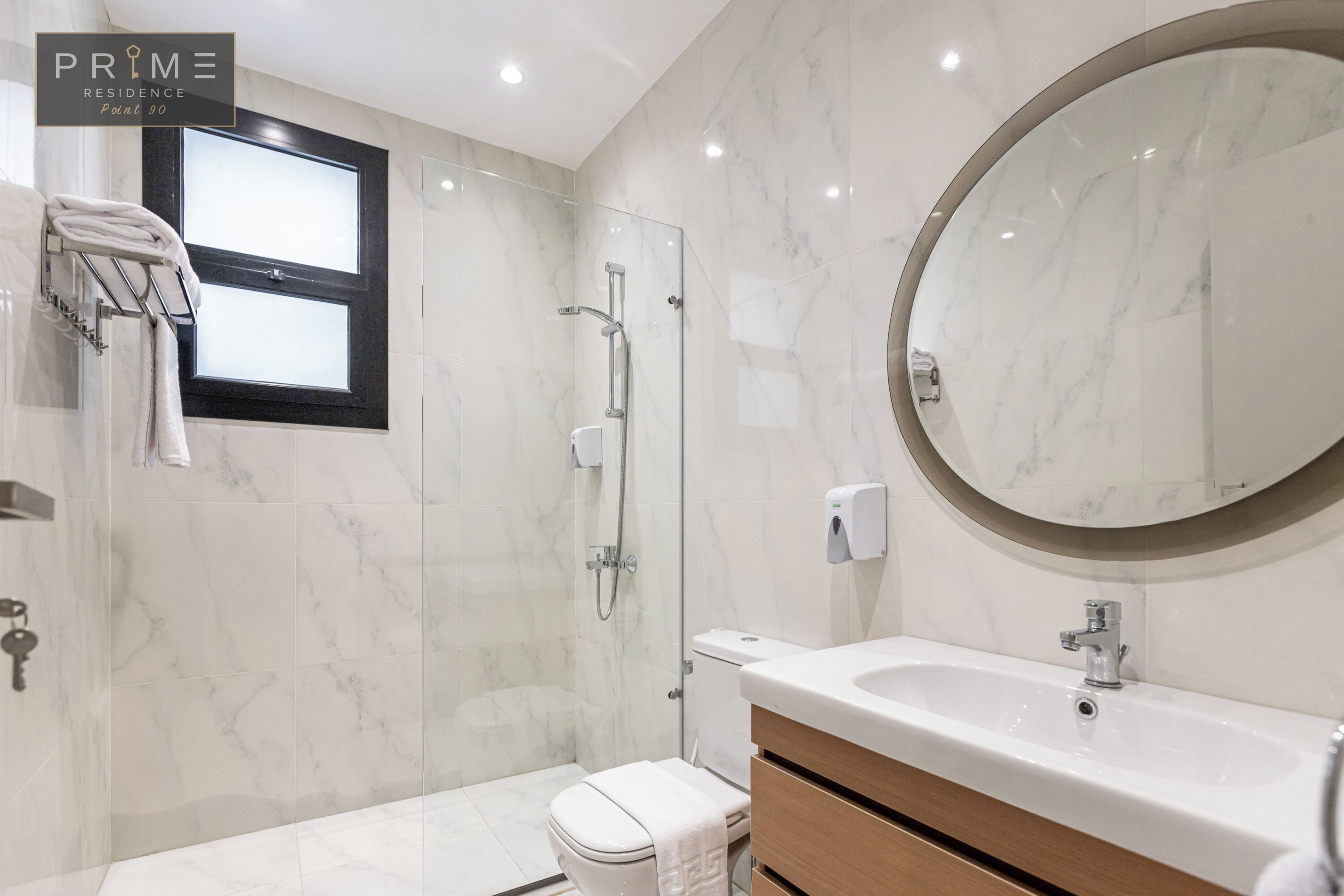 Ein modernes Badezimmer mit Marmorboden, einer gläsernen Duschkabine, einer Toilette, einem Waschbecken mit Spiegel und einem Handtuchhalter.