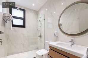A modern bathroom with a marble floor, a glass-enclosed shower, a toilet, a sink with a mirror, and a towel rack.