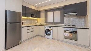 A modern kitchen with a stainless steel refrigerator, a built-in microwave, a washing machine, and a stove. - Prime Residence Point 90 (New Cairo)