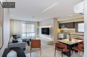 Uma sala de estar moderna com um sofá, uma mesa de centro e uma TV fixada na parede.