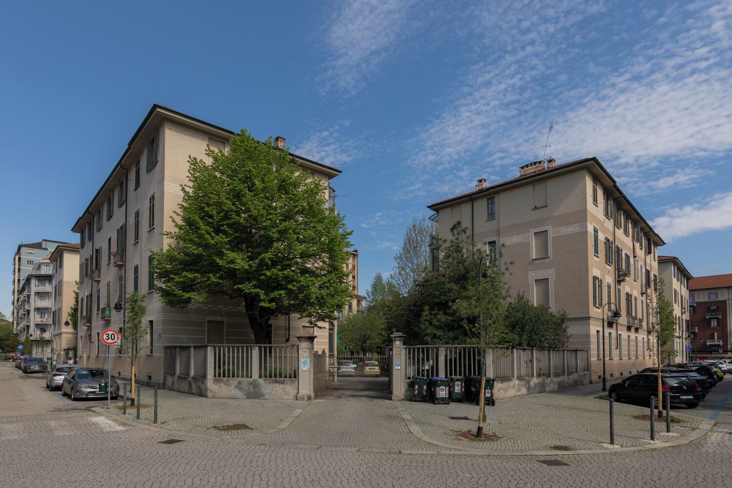 Une vue de rue avec des immeubles, un arbre et des voitures garées.