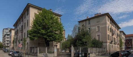 A street view with buildings, a tree, and parked cars.
