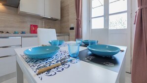 A modern kitchen with white cabinets, a black countertop, and blue bowls and glasses. - The Turin Nest by Wonderful Italy (Turin)