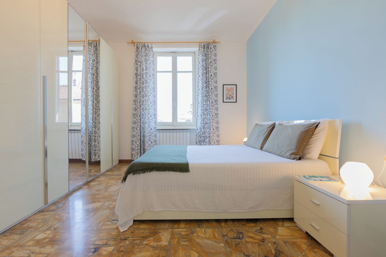 Un dormitorio con cama, mesita de noche y espejo.