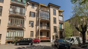 A multi-story residential building with balconies, parked cars, and potted plants. - The Turin Nest by Wonderful Italy (Turin)