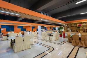 A spacious dining area with multiple tables and chairs, a high ceiling with exposed beams, and a modern design with orange accents. - Vienna International Hotel (Foshan Zumiao Zhangcha Branch) (Foshan)