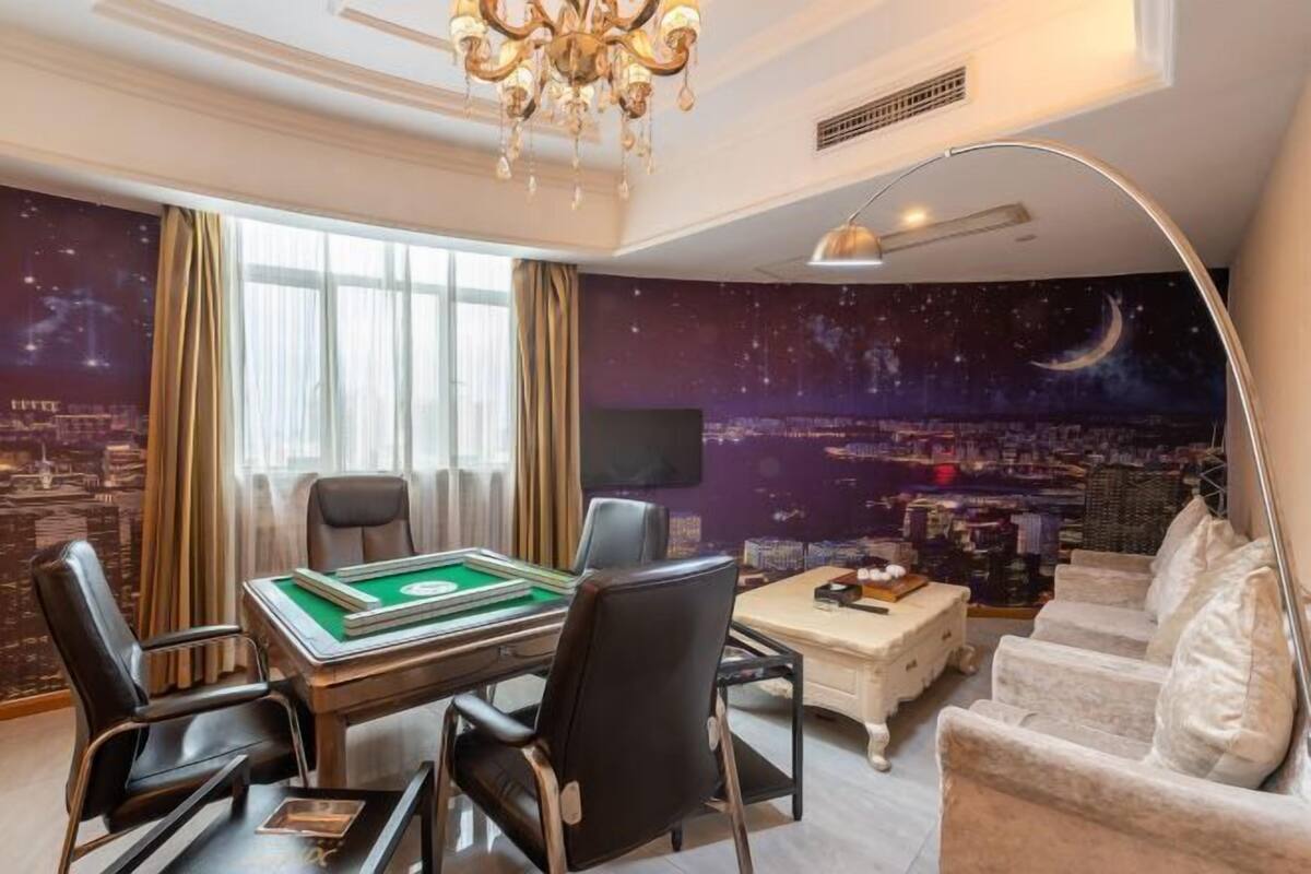 Une pièce dotée d’une table de billard, de sièges confortables, d’un lustre et d’une fresque murale représentant un paysage urbain.