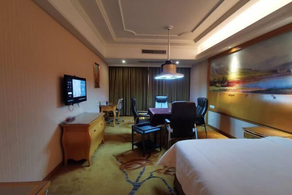 Une chambre d’hôtel équipée d’un lit, d’un bureau, d’une chaise et d’un téléviseur fixé au mur.