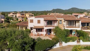 A residential area with multiple houses featuring terracotta roofs, balconies, and a hillside backdrop. - Casa Helen by Wonderful Italy (Olbia)