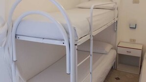 A bunk bed with a white metal frame and a small bedside table with a drawer.