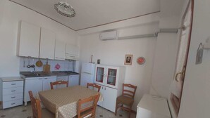 A compact kitchen with white cabinets, a small dining table with chairs, and a refrigerator.