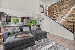 A modern kitchen with dark cabinets, a stainless steel refrigerator, and a window with a view of greenery. - Cabin at Rainier: New-AC-WiFi-Lg. Yard (Ashford)