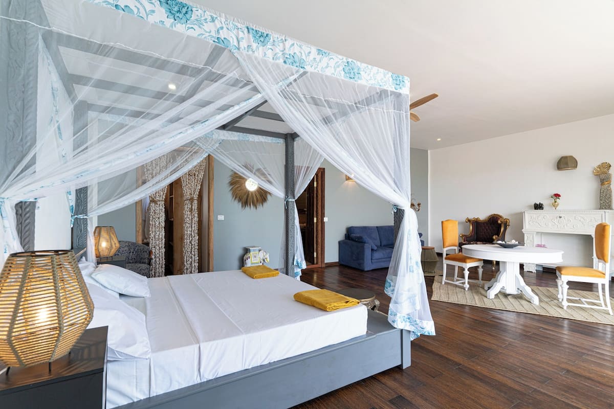 A bedroom with a four-poster bed, a desk, and a chair.