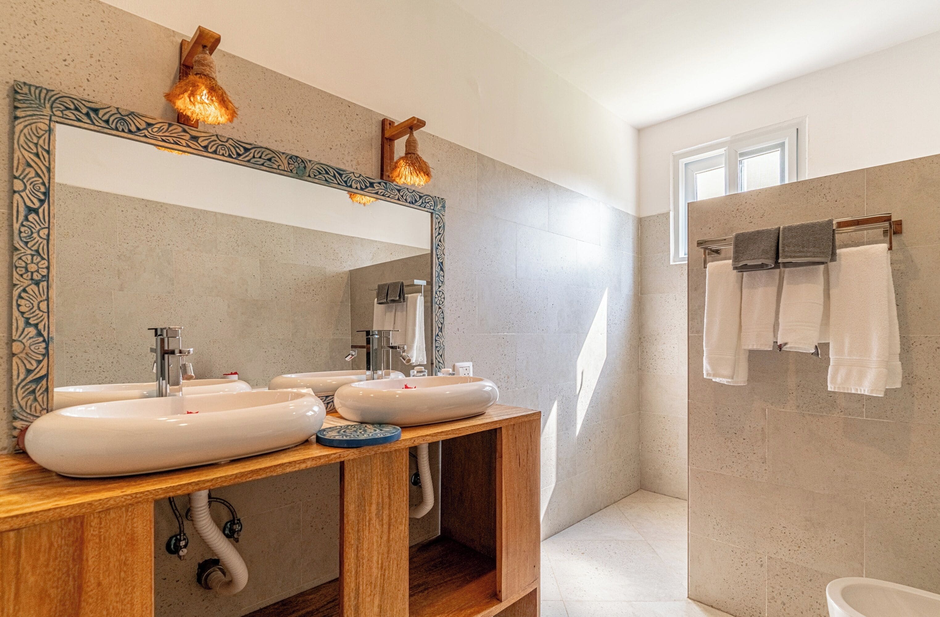 A bathroom with two sinks, a large mirror, and a window.