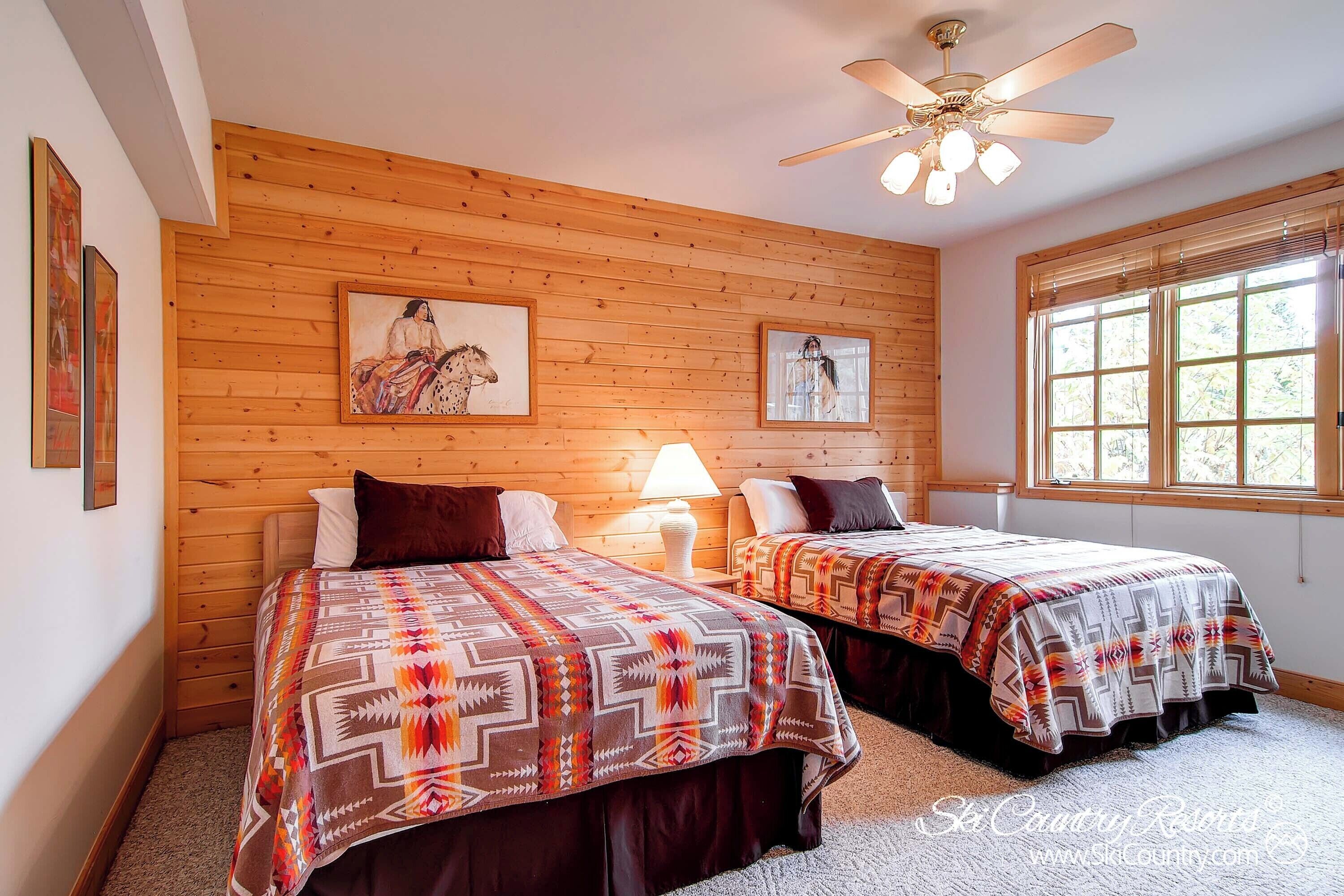 Une chambre avec deux lits, des murs en bois et des ventilateurs de plafond.