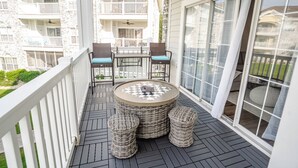 A balcony with wicker furniture, a round table, and a view of a multi-story building. - Amazing vacation rental, great location,pool,close to the beach and golf course  (Myrtle Beach)