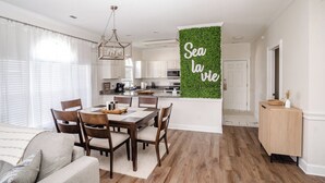 A modern kitchen with white cabinets, a dining area with a wooden table and chairs, and a living room with a sofa. - Amazing vacation rental, great location,pool,close to the beach and golf course  (Myrtle Beach)